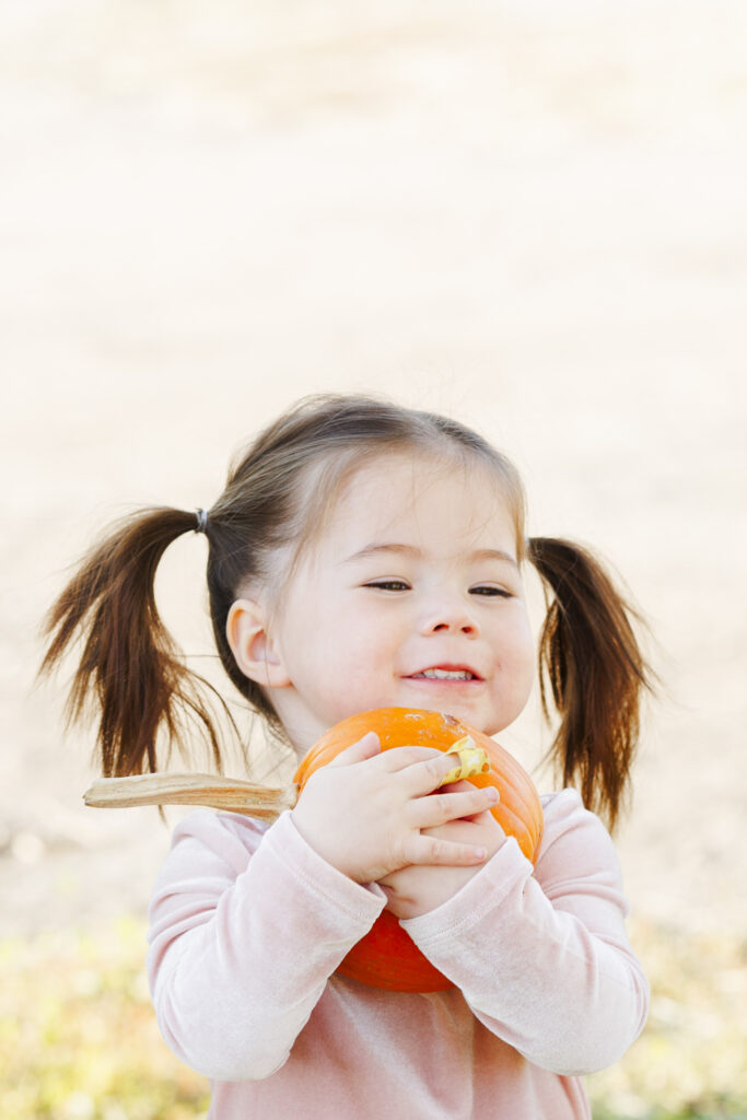 Little girl hugs pumpkin