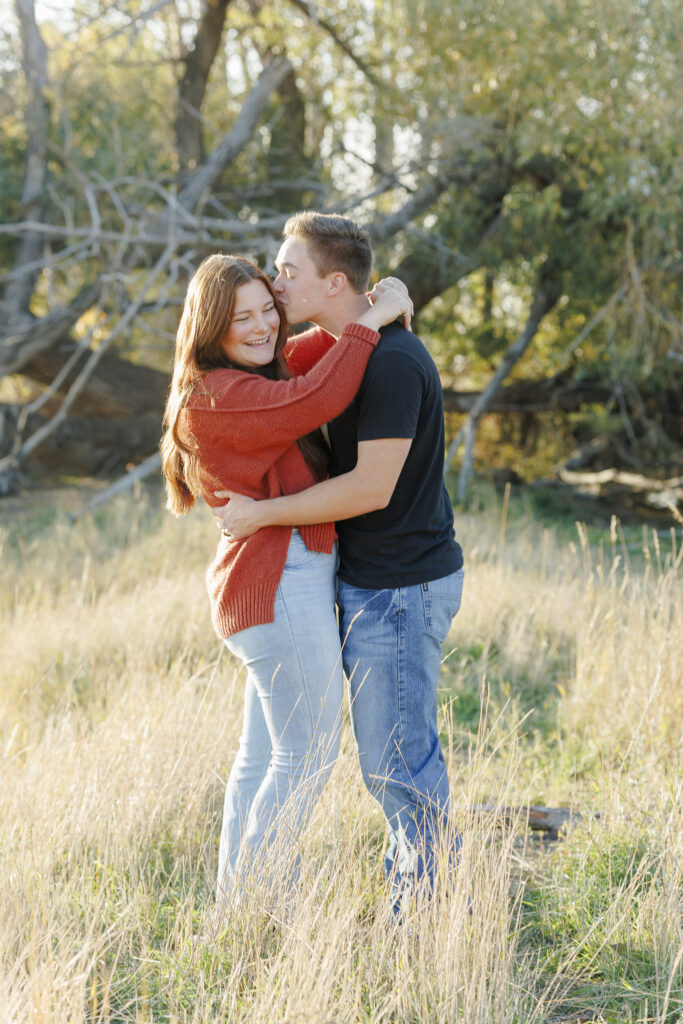 A couple poses in front of a large tree in Montana