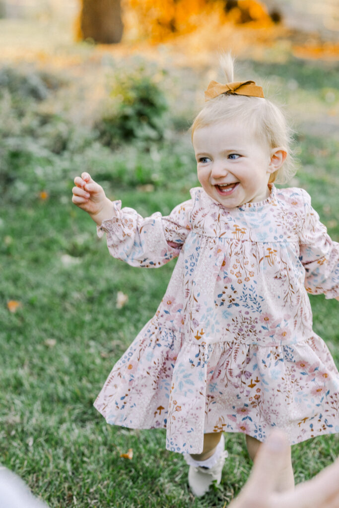 toddler girl laughing while running to dad