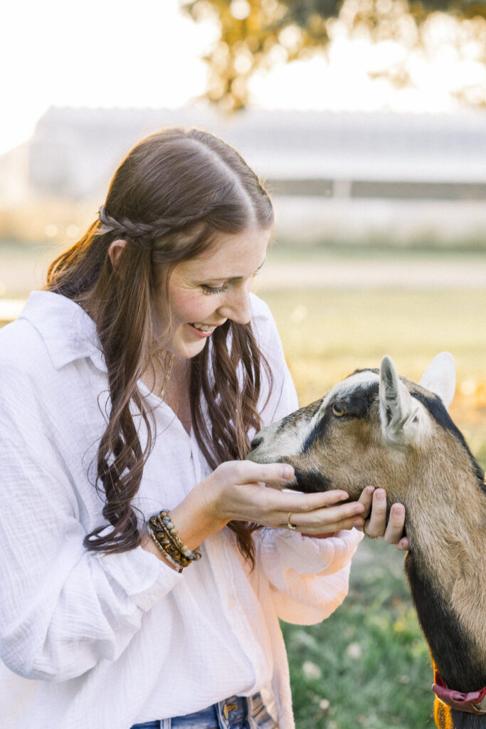 young goat sniffs woman on goat farm in Montana